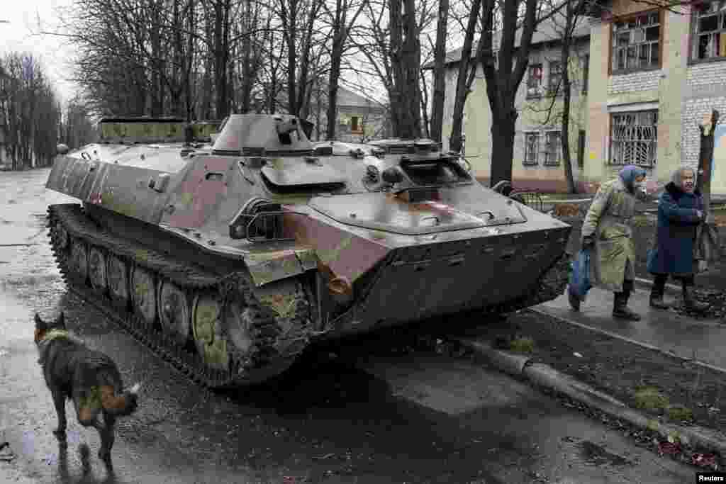 Debaltseve şəhərində Ukrayna hərbi texnikasının yanından keçən qoca qadınlar (Reuters/Marko Djurica)