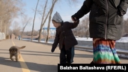 Мальчик Тимофей (в центре) идет по улице со своей матерью. 