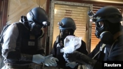 A UN chemical weapons expert holds a plastic bag containing samples from one of the sites of an alleged chemical weapons attack in the Ain Tarma neighbourhood of Damascus in 2013.