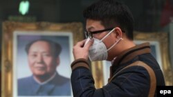 Человек с респираторной маской у портрета бывшего китайского лидера Мао Цзэдуна. Иллюстративное фото.