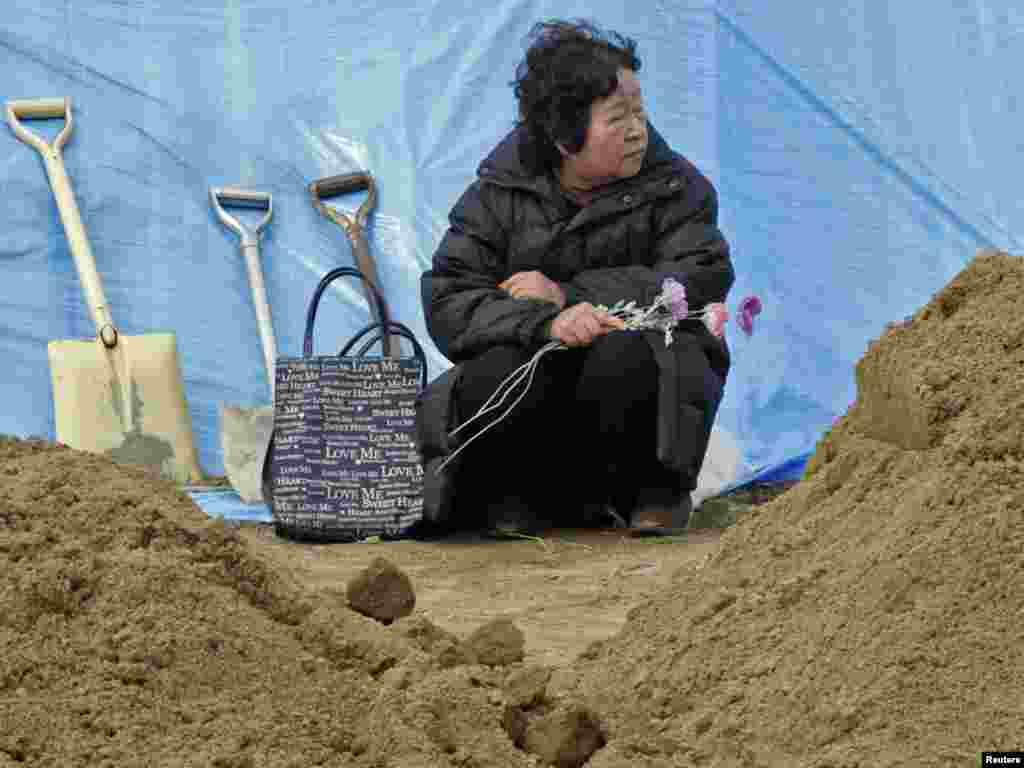 Tokiko Abe, who lost her husband in the March 11 tsunami, waits for his coffin to arrive at a temporary mass grave where victims of the March 11 earthquake and tsunami were buriedPhoto by Yuriko Nakao for Reuters
