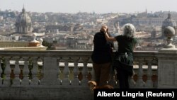 Un cuplu cu un cățel privind panorama Romei, cu bazilica San Pietro în fundal