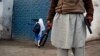 A man with a gun and a metal detector poses for photographers while he stands outside a school in Peshawar.