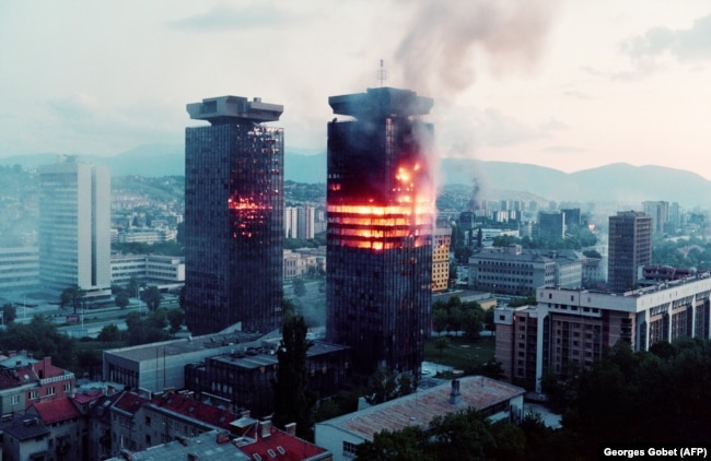 Tüzérségi találatok után égnek a Momo" és az "Uzeir" épületek Szarajevó belvárosában. 1992. június 8-án. Szarajevót 1992-től 1996-ig ostromolta először a jugoszláv, majd a boszniai szerb hadsereg. Nagyjából 14 ezer áldozattal járt az ostrom, köztük több mint ötezer civil erőszakos halálával.