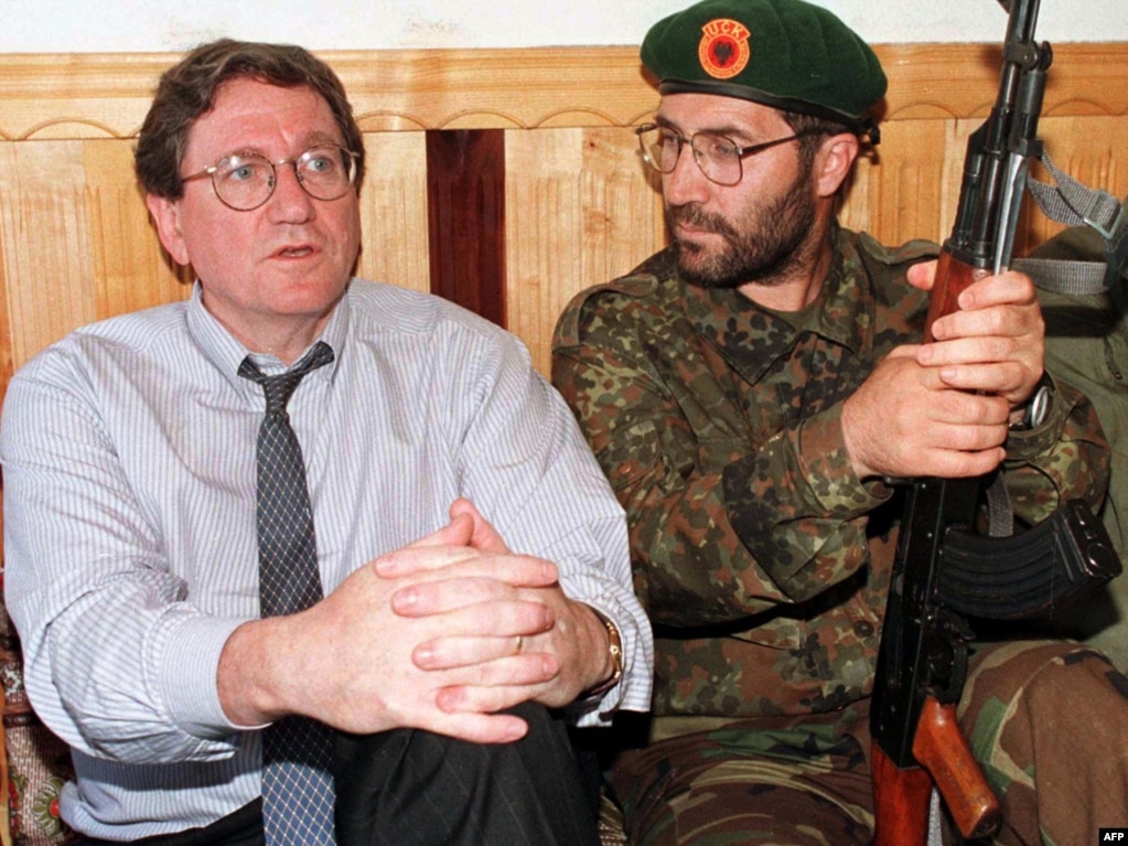 Richard Holbrooke sits with an unidentified member of the Kosovo Liberation Army at KLA headquarters in Junik, southwest of Pristina, during a shuttle diplomatic effort to stop violence in Kosovo on June 24, 1998.
