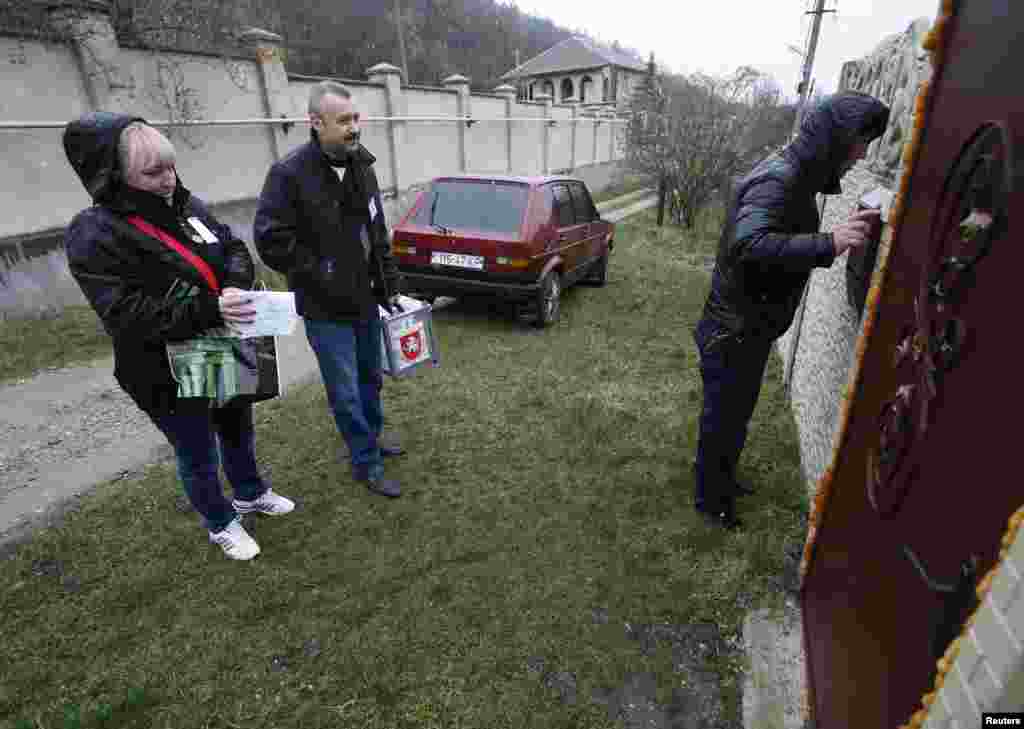Election officials carry a mobile ballot box to a home in the village of Pionerskoye.