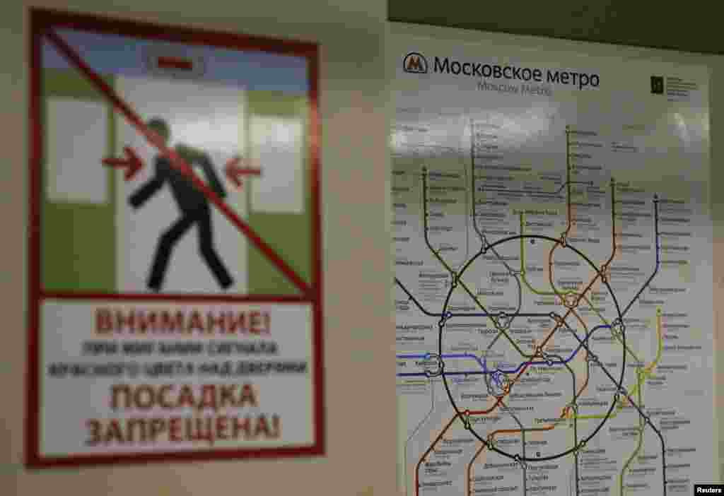A map of the Moscow metro system is seen behind a poster warning passengers to avoid the closing doors on the train.