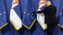 A government official in Belgrade arranges flags prior to a press conference during a visit by a European enlargement delegation. (file photo)