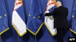 A government official in Belgrade arranges flags prior to a press conference during a visit by a European enlargement delegation. (file photo)