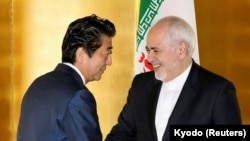 Japanese Prime Minister Shinzo Abe greets Iranian Foreign Minister Mohammad Javad Zarif at the start of their bilateral meeting in Yokohama, August 28, 2019