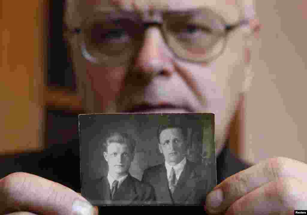 62-гадовы Ўладзімер Колас трымае фатаграфію свайго бацькі Георгія і дзеда Данілы. Сваякі Коласа правялі некалькі гадоў у выгнаньні, але выжылі і вярнуліся дадому ў 1950 годзе. 