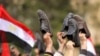 Antigovernment protesters wave their shoes outside a state building in Cairo,