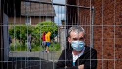 Rumunski radnik stoji iza ograde na ulazu u klaonicu Rosendahl u Njemačkoj gdje je u maju zaraženo korona virusom više desetina radnika većinom migranata,12. maja 2020. godine.