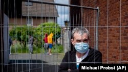 Rumunski radnik iza ograde postavljene na ulazu u kuće gde su smešteni Rumuni zaposleni u klanici u Rozendalu, 12. maj.