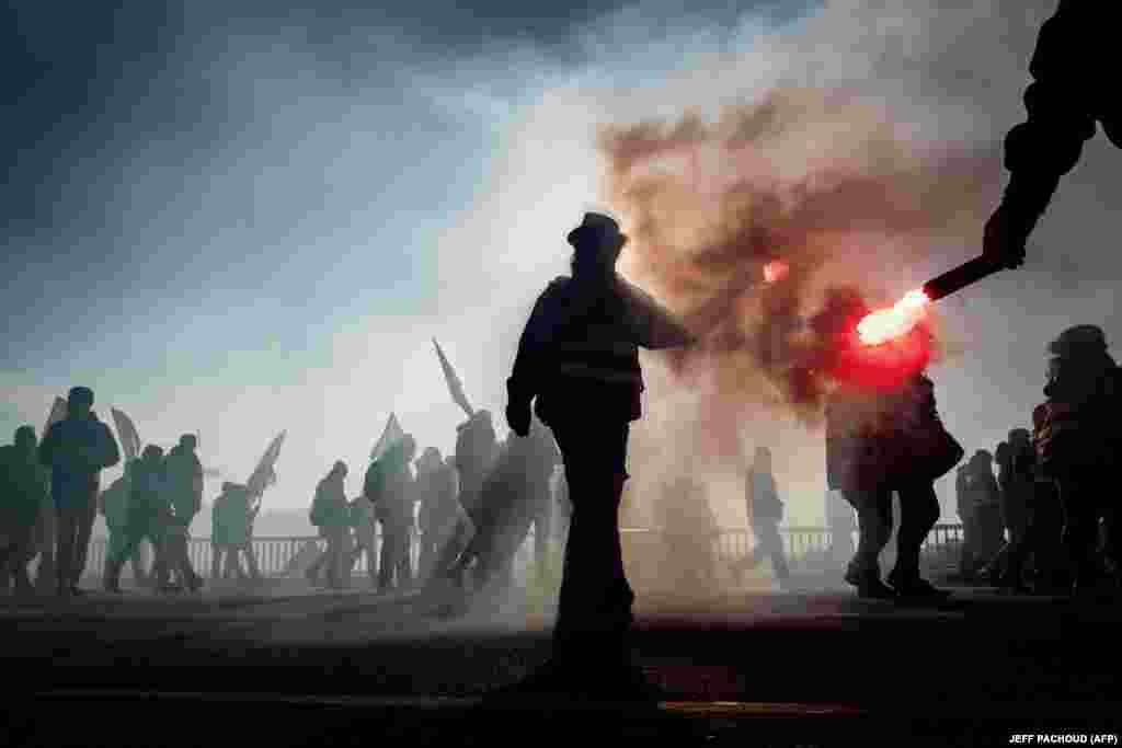 Protesters hold flares during a demonstration on December 10 in Lyon as part of the sixth day of massive strike action over the French government&#39;s plans to overhaul the pension system. (AFP/Jeff Pachoud)