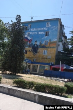 Pictură murală cu un marinar care seamana cu Putin sub lozinca „bine ai revenit acasă”