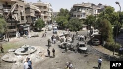 Syrians gather to inspect the damage at the site of a suicide bomb attack in Damascus's eastern Tahrir Square district on July 2.