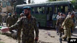 Afghan National Army soldiers stand next to the wreckage of a military bus at the site of a suicide attack in Kabul on July 2,2014