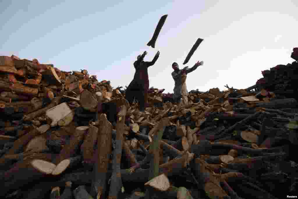 Men throw wood from a pile of logs into a supply truck at a timber warehouse in Lahore, Pakistan. (Reuters/Mohsin Raza)