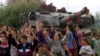 Shqiptarë etnikë festojnë para një tanku britanik të NATO-s, tytën e të cilit e kanë zbukuruar me lule, ndërsa trupat e para të NATO-s vendosen në kryeqytetin e Kosovës, Prishtinë, më 13 qershor 1999.