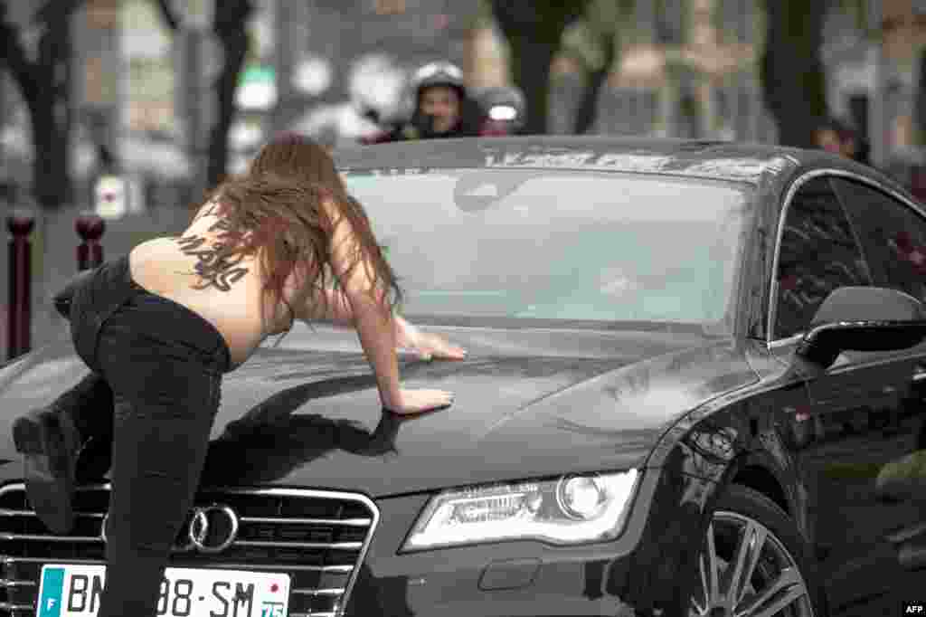 A topless Femen activist jumps on the car carrying former IMF chief Dominique Strauss-Kahn (not seen) as he arrives for his "aggravated pimping" trial in Lille on February 10. (AFP/Denis Charlet)