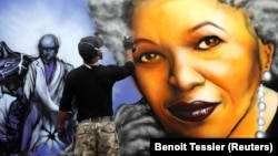 یک هنرمند نقاش در حال ترسیم تصویری از تونی موریسون برنده جایزه نوبل بر دیواری در پاریس