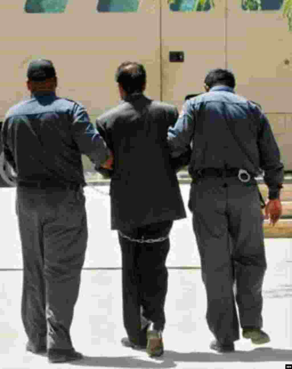 Saddam Hussein is led away in chains from a court hearing, July 2004. Iraqis pressed multiple charges against him, while Iran wanted him for crimes allegedly committed during the Iran-Iraq War.