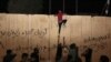 An Iraqi protester tries to climb the concrete wall of the Iranian Consulate in Karbala on November 3.