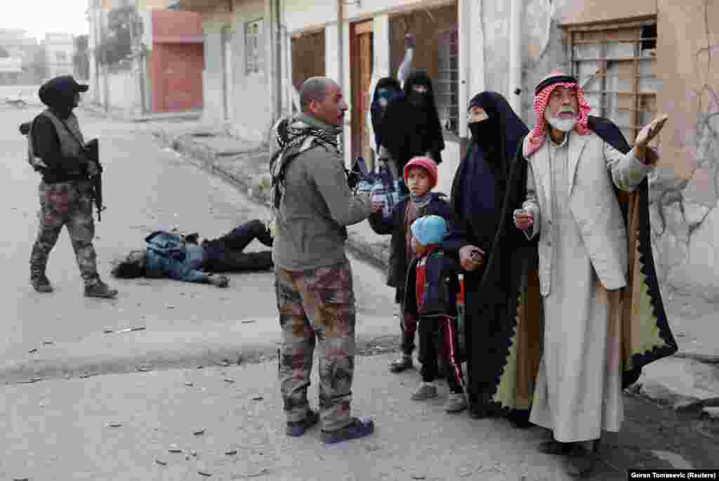 Civilians attempting to flee Mosul photographed near the body of an Islamic State fighter on February 28. An estimated 1.5 million civilians are still inside the city.