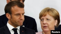 France's President Emmanuel Macron and Germany’s Chancellor Angela Merkel during a news conference at the G20 summit in Osaka