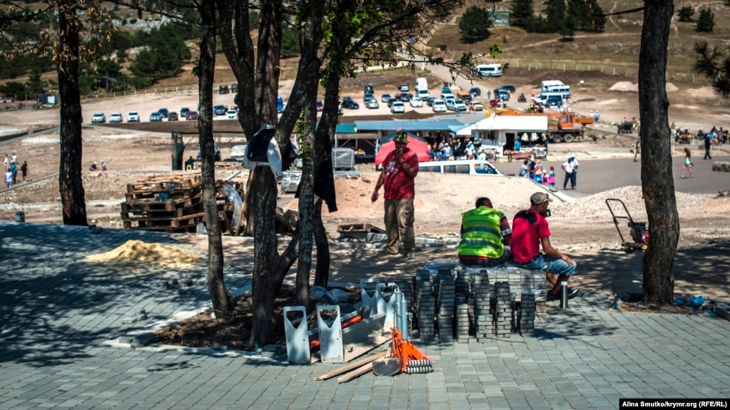 Работники заканчивают укладку плитки на месте снесенных торговых палаток на вершине плато