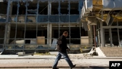 A man walks past a building damaged in recent shelling in Donetsk's Kyivskiy district, near the airport, on October 7.