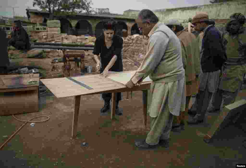 Afridi talks to a carpenter at a workshop on the outskirts of Islamabad.