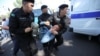 Полицейский спецназ несет задержанного к служебному микроавтобусу. Алматы, 21 сентября 2019 года.