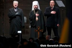 Ukrainian President Petro Poroshenko (left), parliamentary speaker Andriy Parubiy (right), and the newly elected head of the independent Ukrainian Orthodox Church, Metropolitan Epifaniy, sing the national anthem at St. Sophia's Cathedral in Kyiv on December 15.