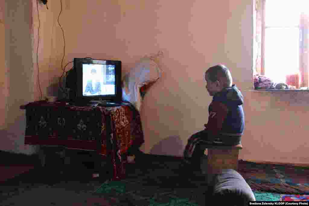 Four-year-old Kurbanbek is the youngest resident of the half-abandoned village. Here, he watches local Tajik television.