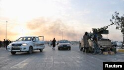 Fighters of the Islamic State of Iraq and the Levant (ISIL) stand guard at a checkpoint in the northern Iraqi city of Mosul on June 11.