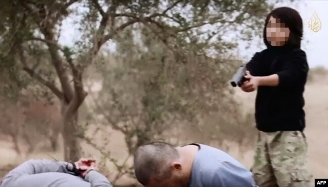 Кадр пропагандистского видео исламистов, на котором мальчик-боевик Абдулла, предположительно из Казахстана, расстреливает двух мужчин, обвиненных в шпионаже против экстремистской группировки «Исламское государство».