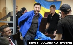 Тодішній керівник «РИА Новости Украина» Кирило Вишинський (посередині), якого в Україні звинуватили, зокрема, у державній зраді та незаконному зберіганні зброї. Київ, 19 липня 2019 року