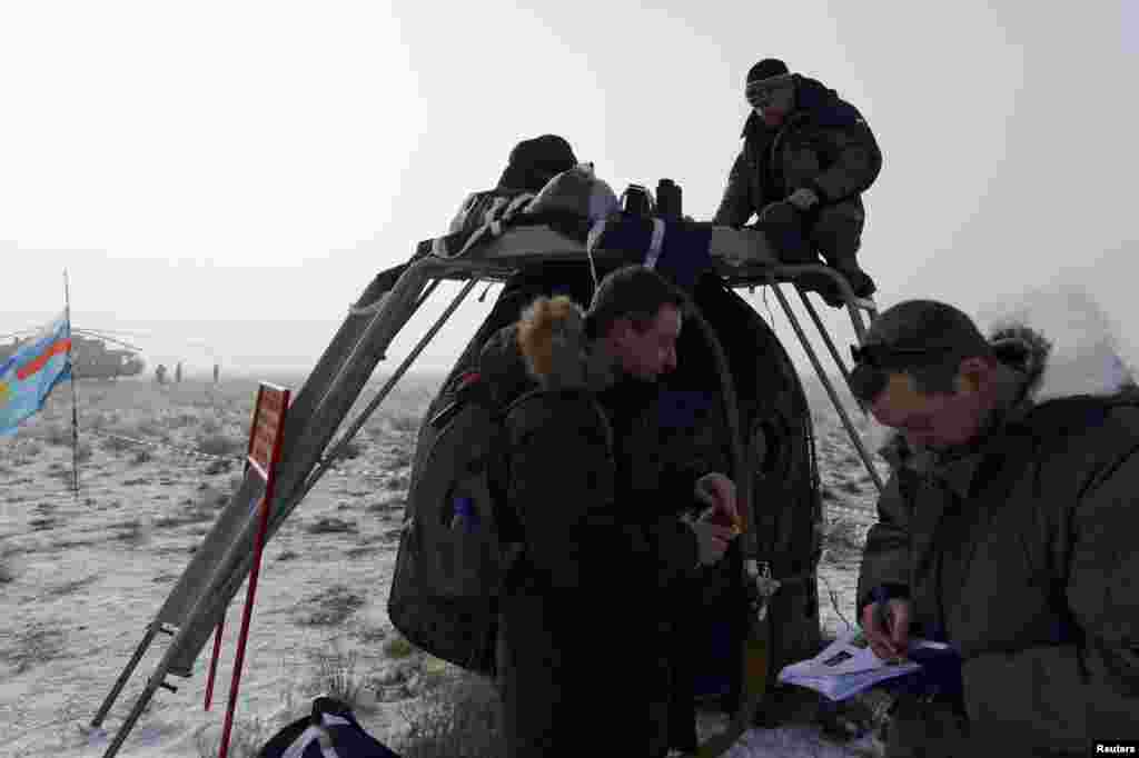 Personnel from Russia&#39;s space agency check the Soyuz TMA-14M capsule shortly after its landing southeast of the town of Zhezkazgan, Kazakhstan, on March 12. A NASA astronaut and two Russian cosmonauts landed safely after a 167-day mission aboard the International Space Station. (Reuters/Vasily Maximov)