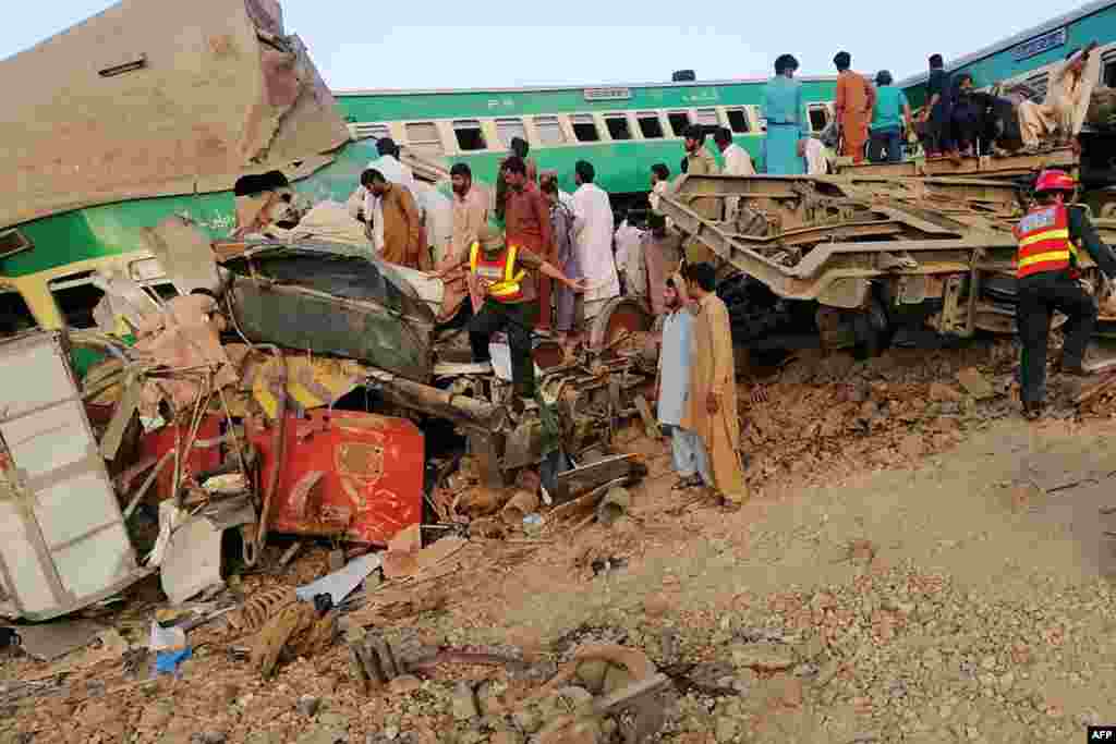 Pakistani rescue personnel and local residents search for victims in a wreck train carriage