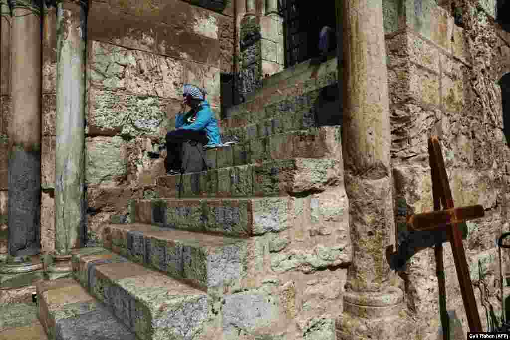 A pilgrim sits by the closed gate of the Church of the Holy Sepulchre in Jerusalem&#39;s Old City. Christian leaders took the rare step of closing the Church of the Holy Sepulchre, built at the site where Jesus is believed to buried, in protest at Israeli tax measures and a proposed property law. (AFP/Gali Tibbon)