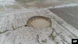 Iran - a sinkhole caused by land subsidence, caused by excessive ground water usage, caused by drought. AP video screen grab