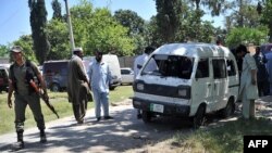 Pakistani police officials inspect the site of a roadside bomb explosion in Peshawar on May 18.