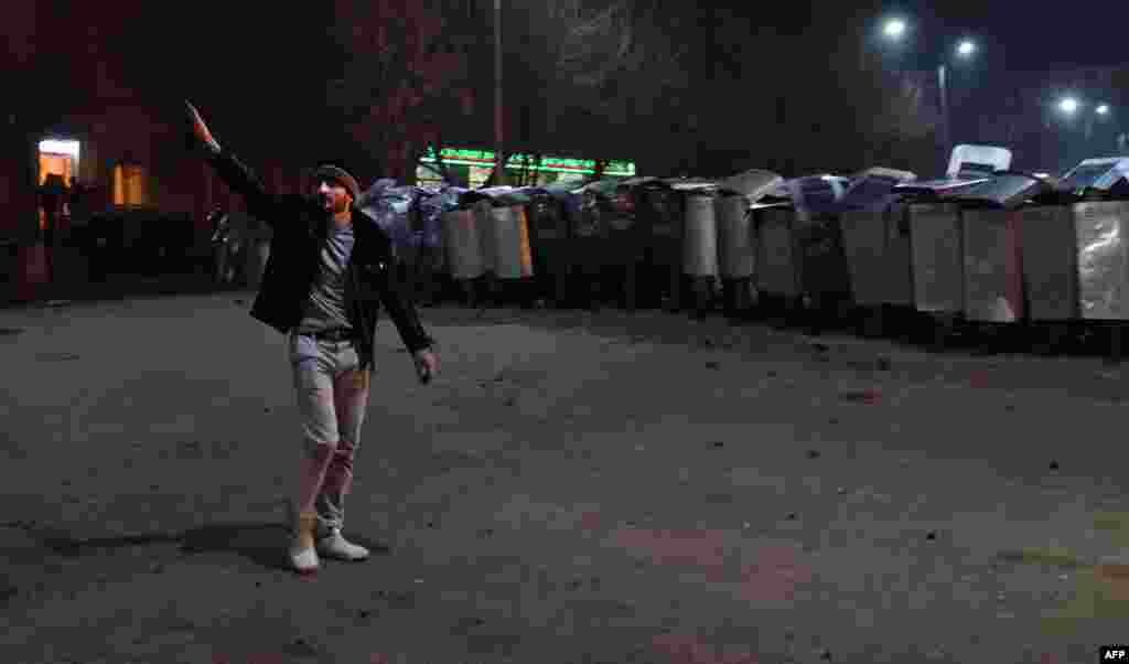 A man gestures in front of a row of Armenian police officers holding up their shields as they stand guard during clashes with protesters at a demonstration near the Russian Consulate General in Gyumri, where Russian soldier Valery Permyakov is suspected of having murdered a family of six. Protesters are demanding that Russia hand over the suspect for trial. (AFP/Karen Minasyan)