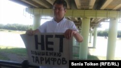 Житель города Атырау Талгат Аян держит плакат с надписью: "Нет повышению тарифов". 12 июля 2015 года. 