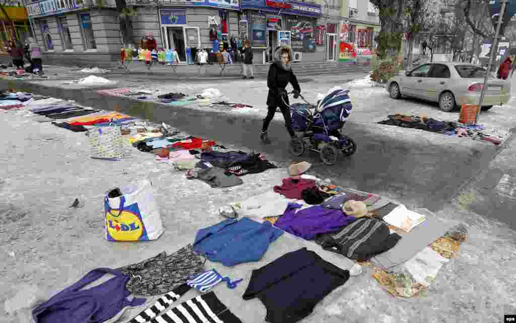 A Moldovan woman pushes a baby stroller while passing a flea market were people sell secondhand goods, displayed on the pavement, on a boulevard in Chisinau, Moldova. (epa/Robert Ghement)