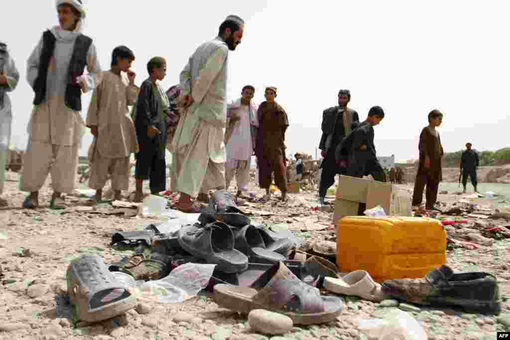 Men walk amidst sandals, mostly from victims of a bomb blast, strewn at the roadside on the outskirts of Kandahar, Afghanistan. An improvised bomb went off in a weekly bazaar outside Kandahar city, killing four civilians and wounding 22 others. (AFP/Jangir)