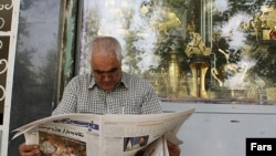 Iran, Tehran -- A man reads a newspaper