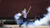 FILE: A Kashmiri student throws back a tear smoke shell at Indian police personnel during clashes in Srinagar, the summer capital of Indian Kashmir on May 14.